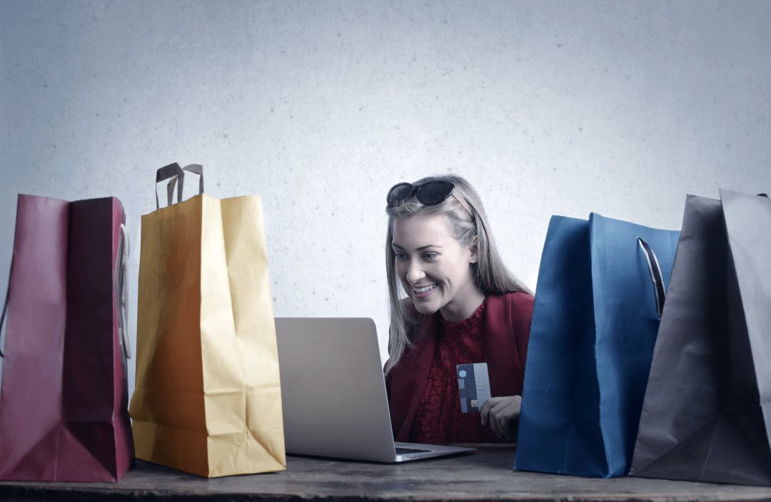Retail shop owner working on a laptop among shopping bags